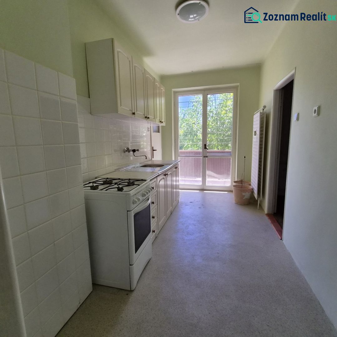 A kitchen in a 3-room apartment with a stove and a view of the balcony.