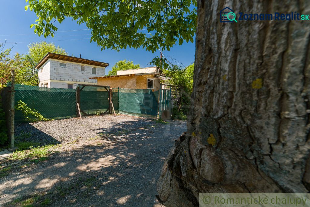 A cottage in Bernolákovo surrounded by greenery and a fenced yard.