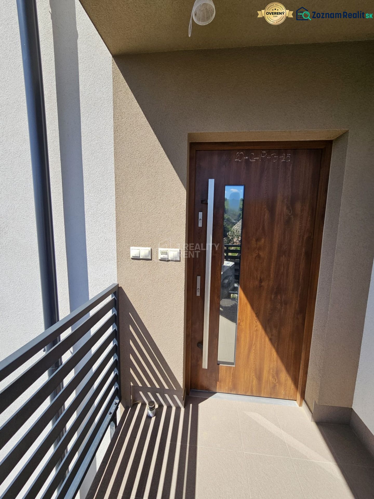 Entrance door to a one-room apartment with a wood decor and a balcony railing.