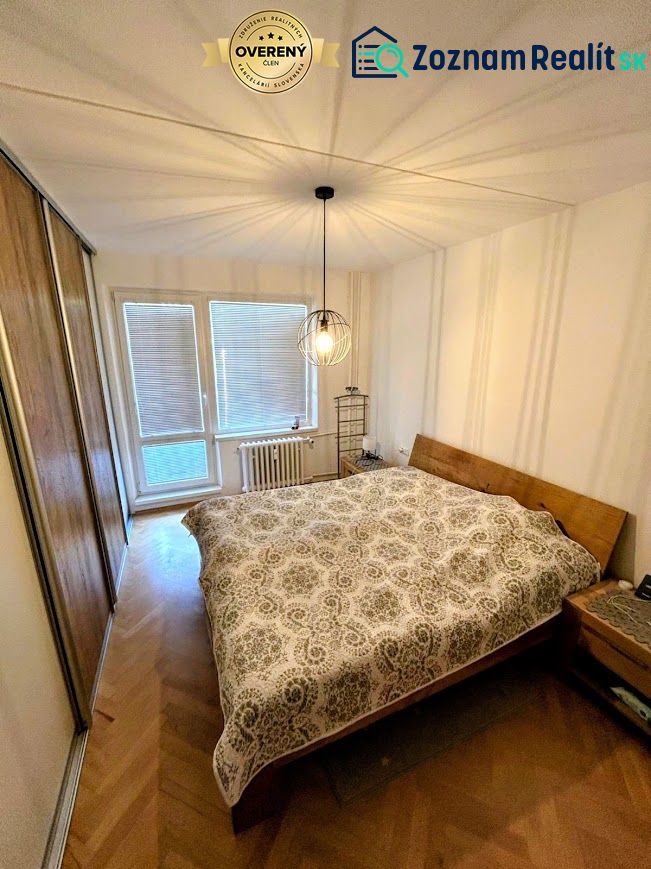 Bedroom in a 3-room apartment with a wood-patterned floor and practical lighting.