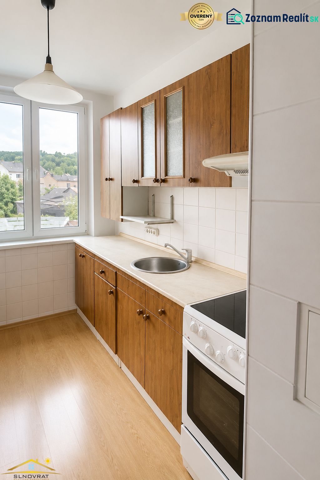 The kitchen of a 3-room apartment with a door to the balcony and a floor with a wooden decor.