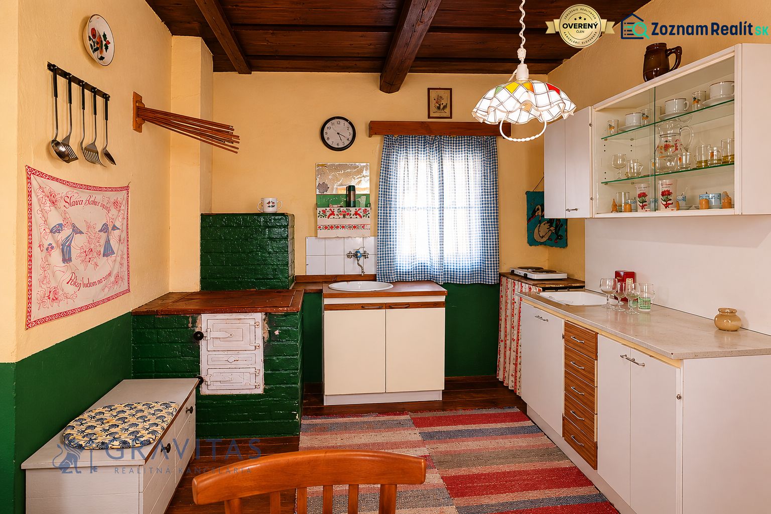 A kitchen in a cottage with traditional furnishings, a fabric curtain, and a floor with a wooden decor.