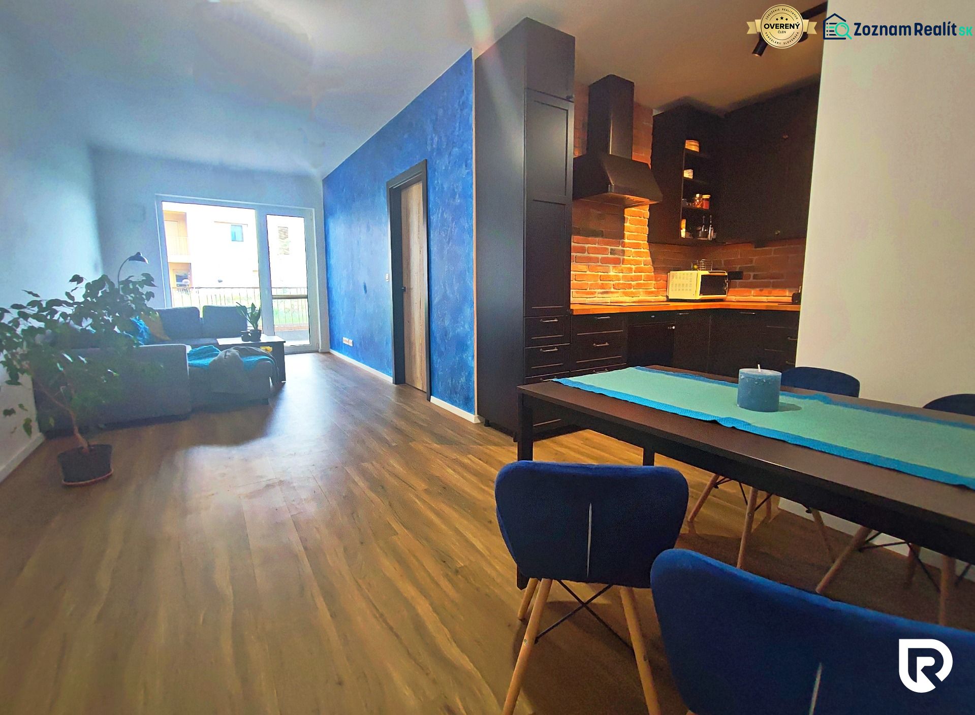 Living room with kitchen in a two-room apartment, with a wooden decor floor and colorful walls.