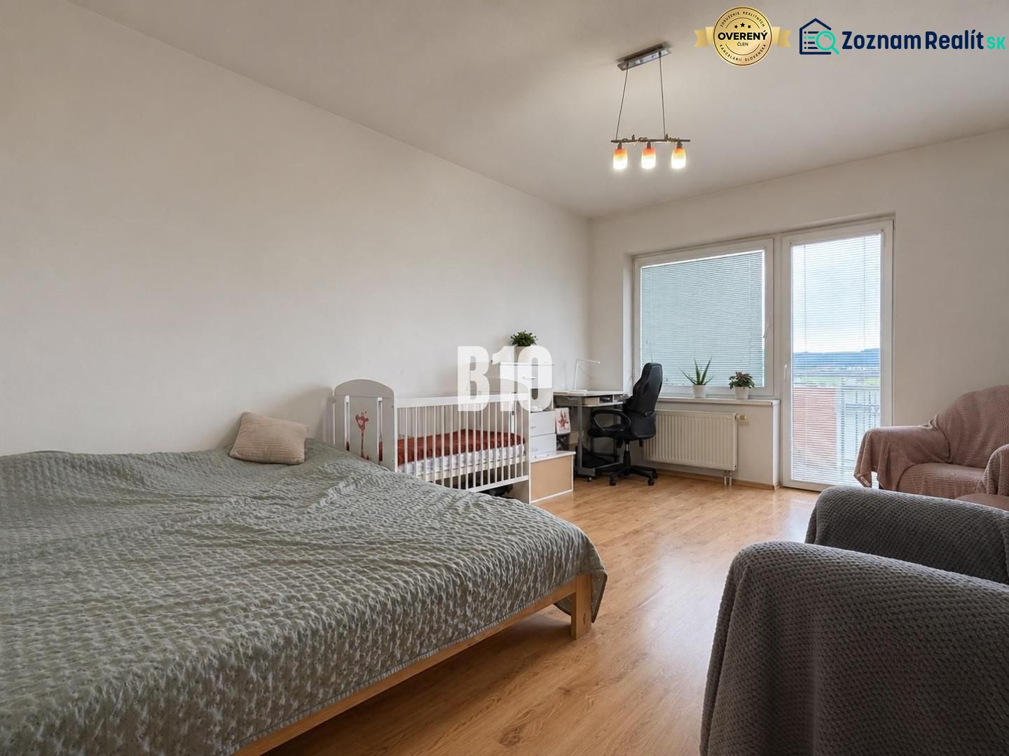 A bright room with a bed, a crib, and a wooden decor floor in a 2-room apartment.
