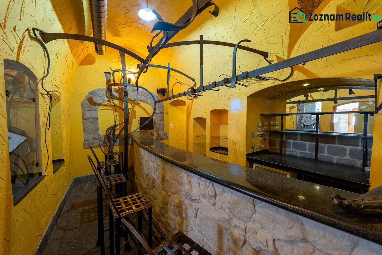 The interior of the building with yellow walls, a stone bar, and metal chairs.