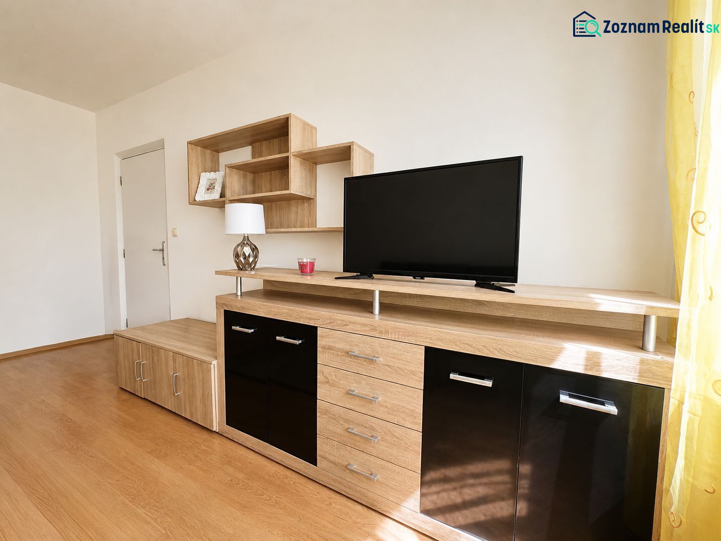 A living room with wood decor furniture and black elements in a studio apartment.