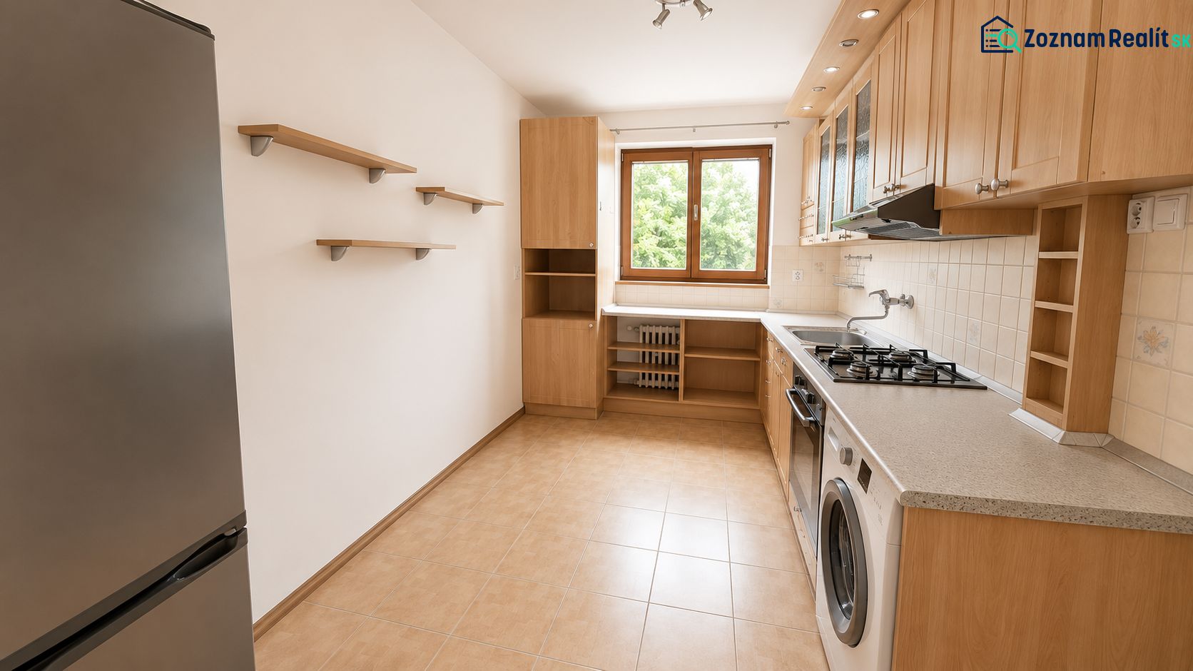A kitchen in a 2-room apartment with wooden cabinets, appliances, and a window.