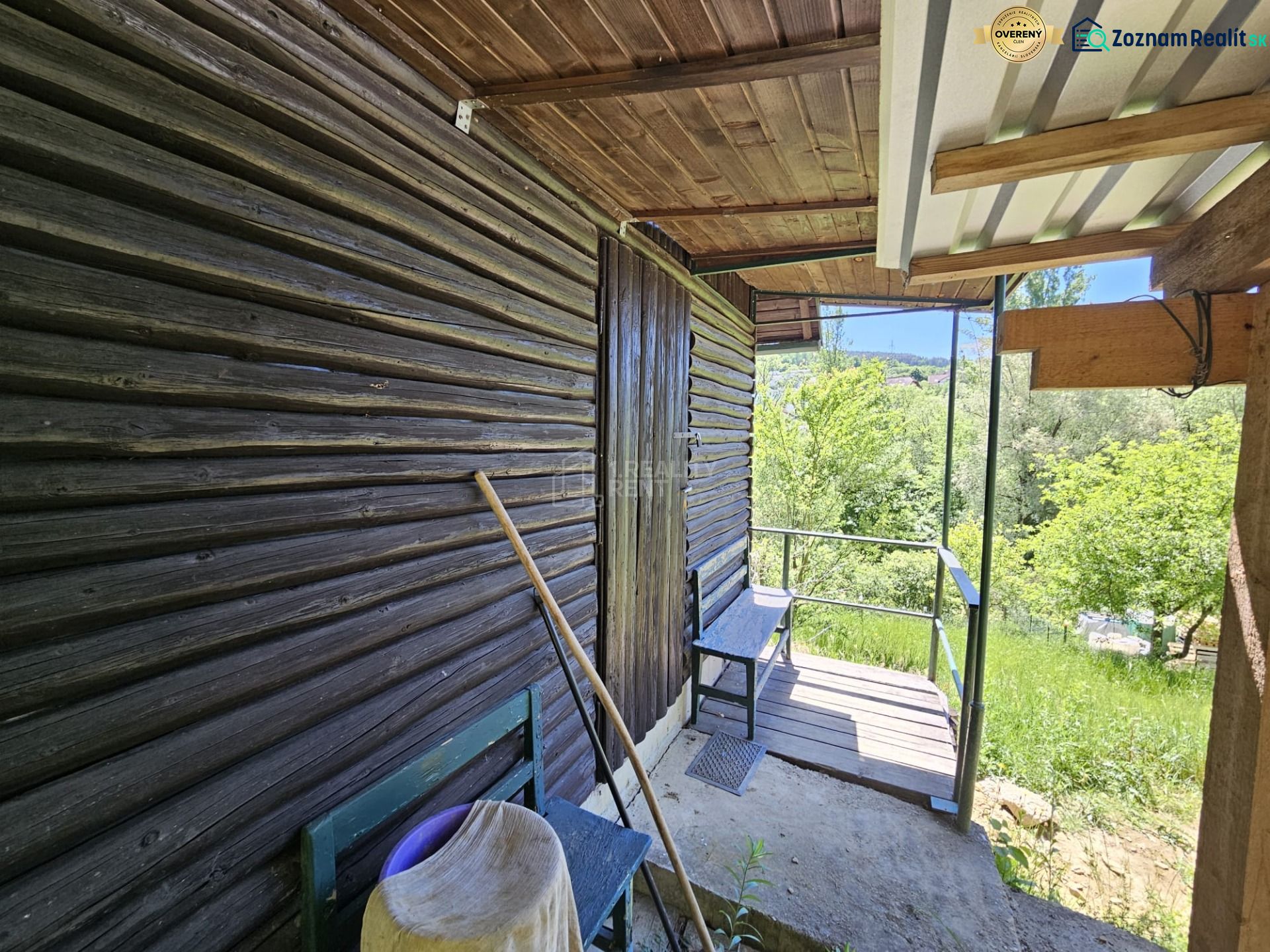 A cottage in Budatín with wooden cladding, a terrace, and a view of the green garden.
