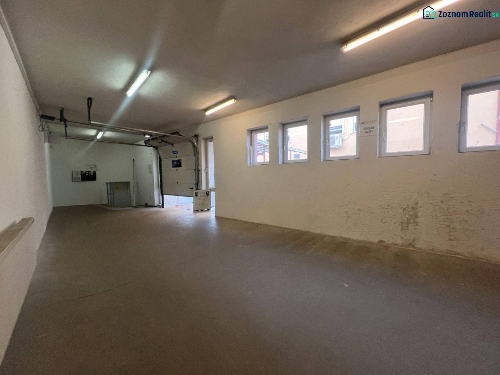 The interior space of warehouses and halls with windows and a garage door.