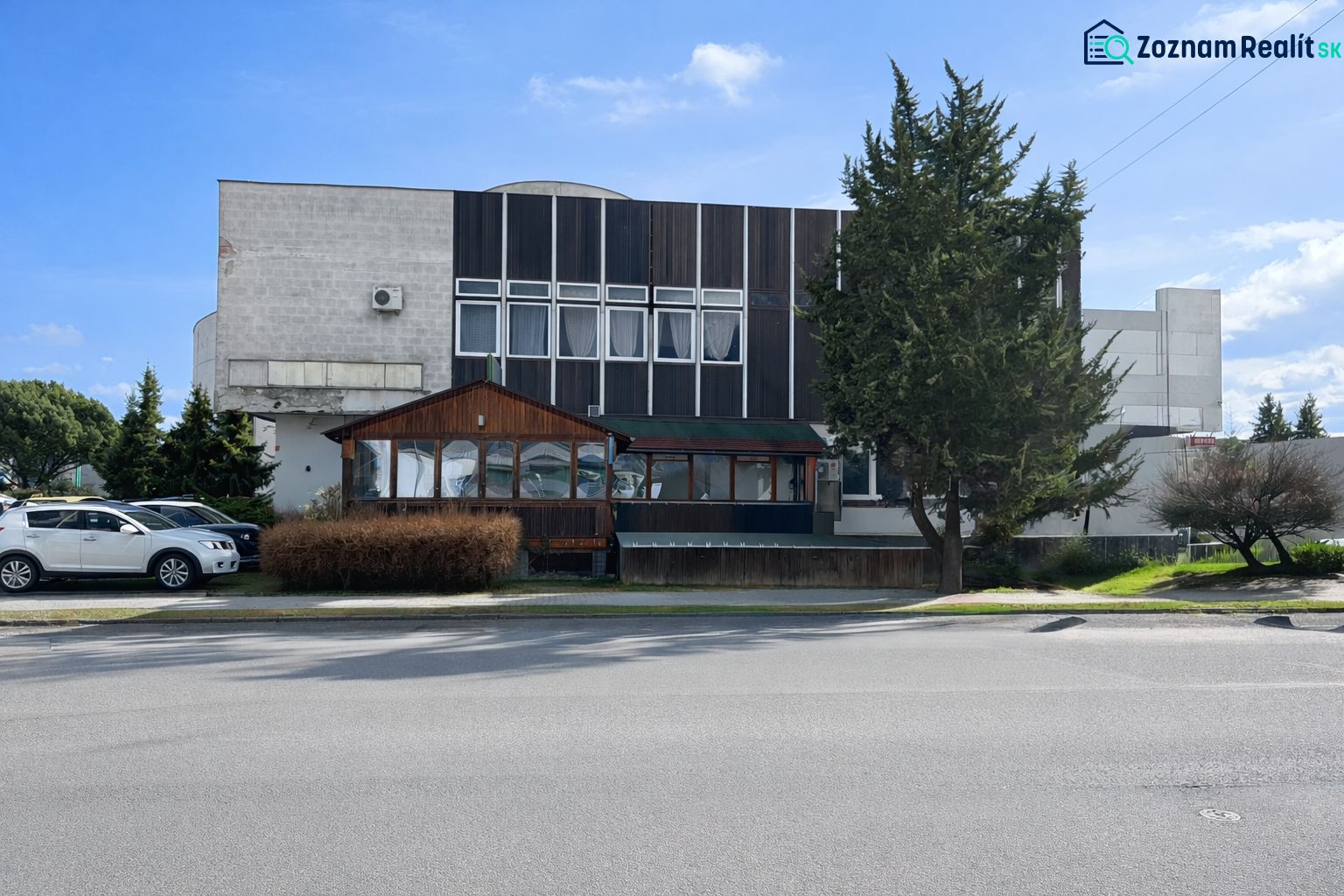 The exterior of the gastro premises in Žiar nad Hronom, surrounded by trees and parked cars.