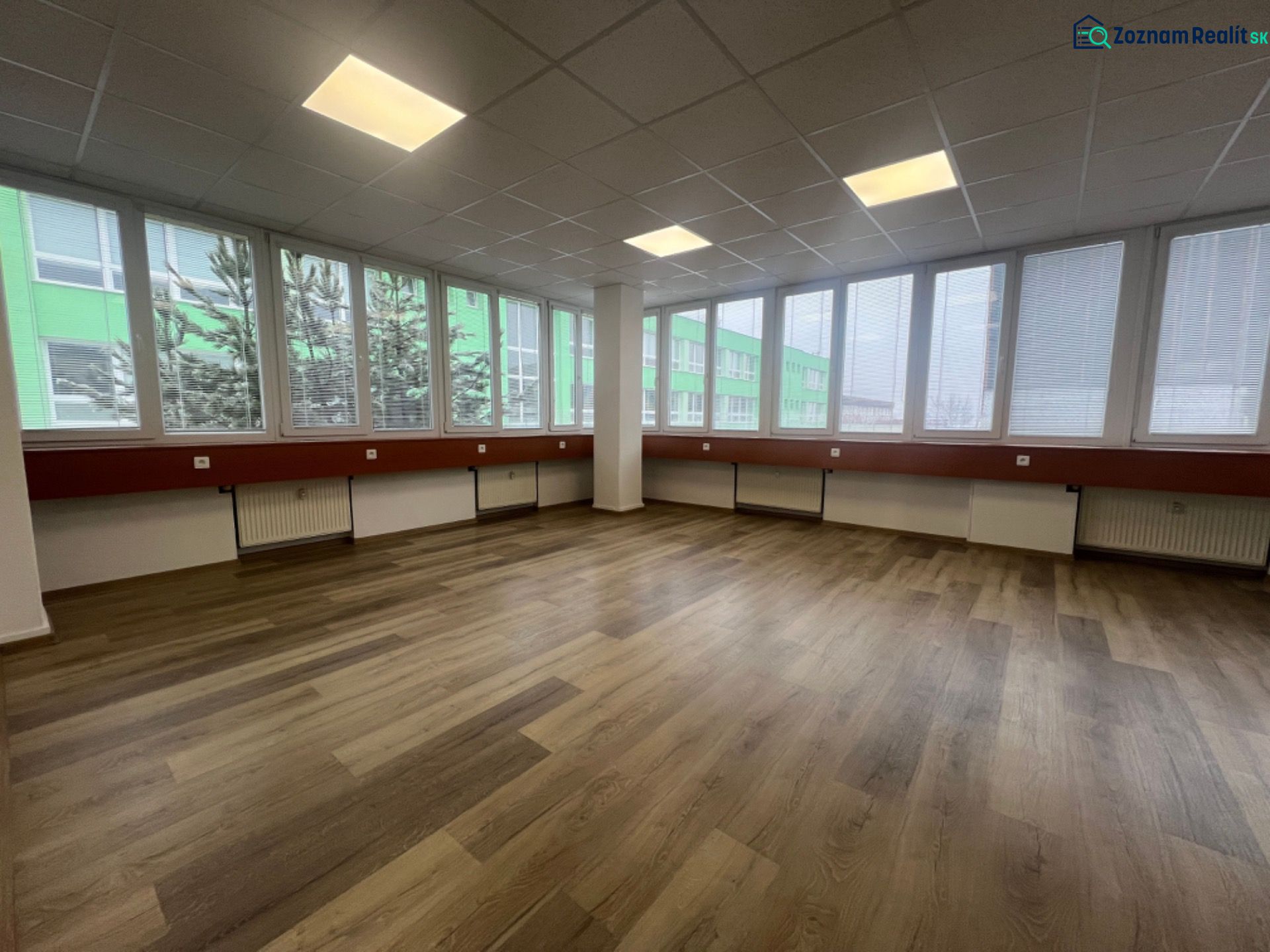 Large office spaces with wood-patterned flooring and large windows.