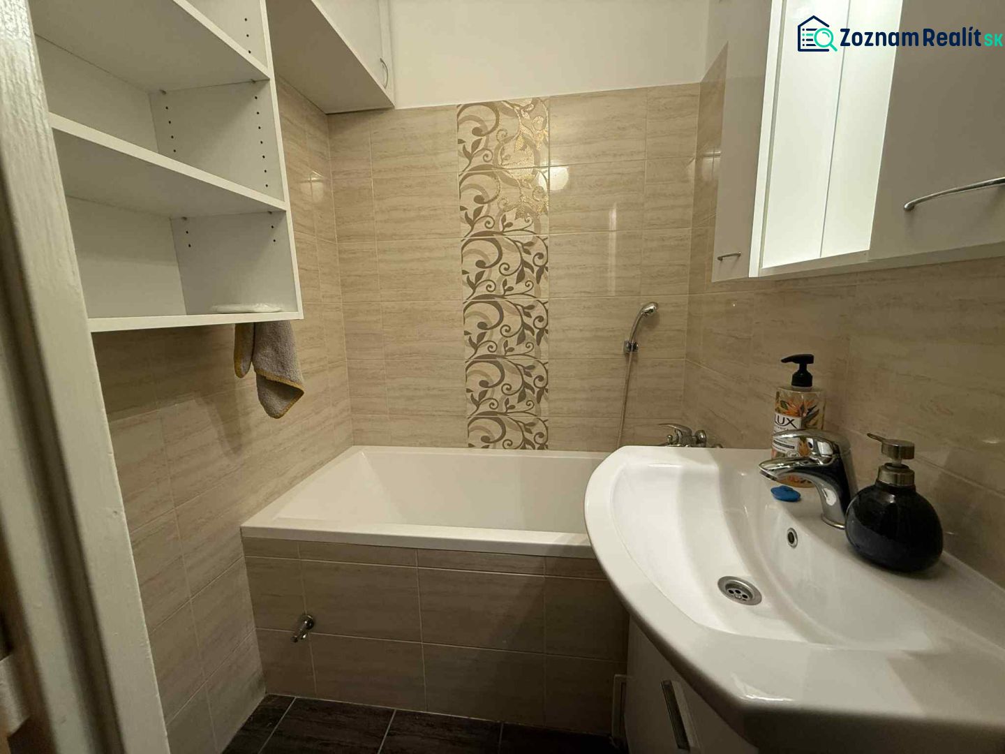A bathroom with a bathtub in a 4-room apartment, with storage shelves and decorative tiles.