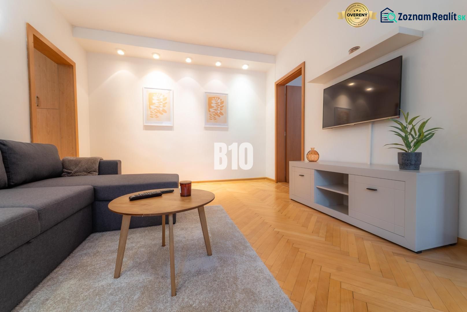 Living room with a TV on the wall, a gray sofa, and a floor with a wood decor.