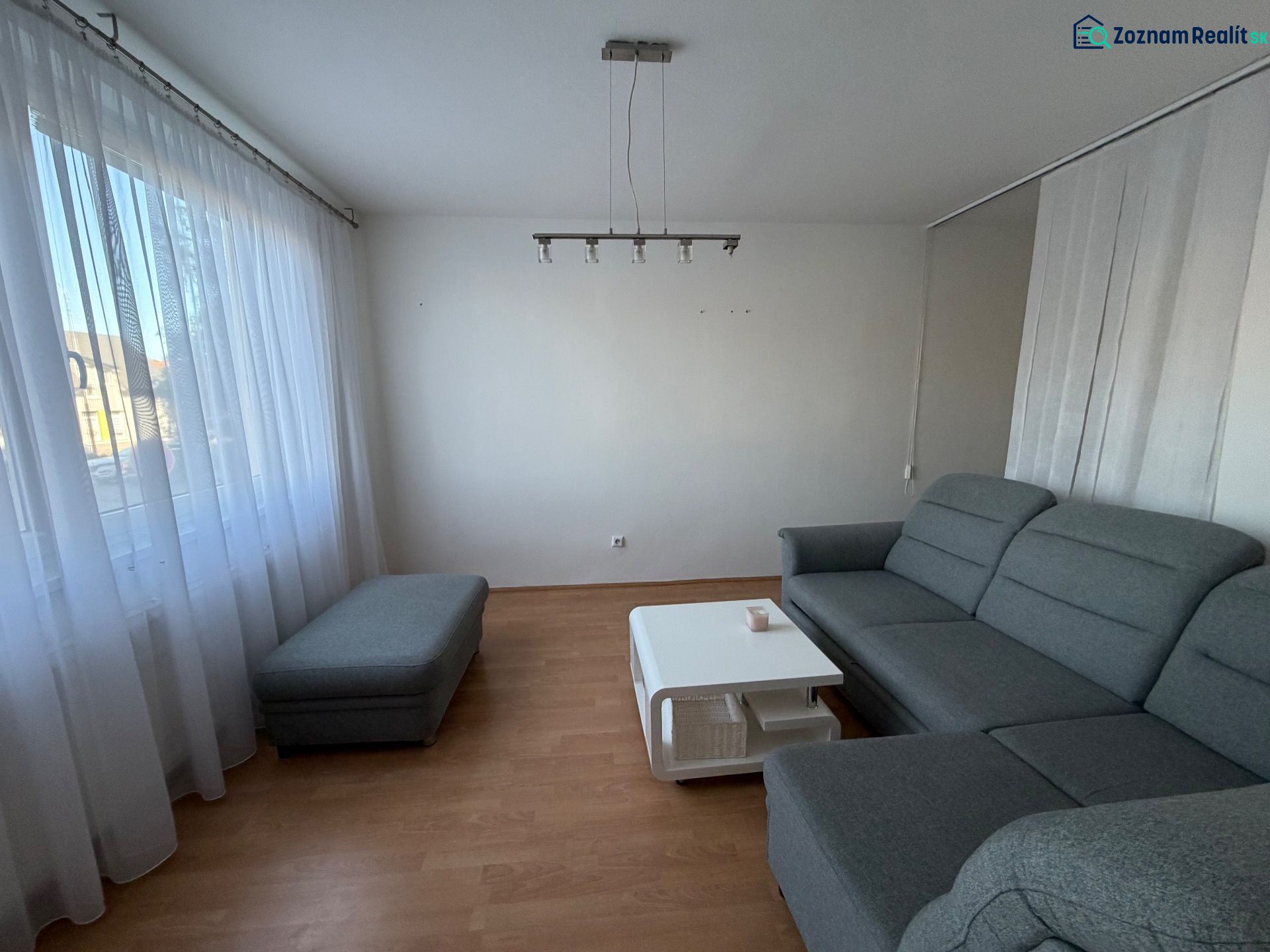 Living room with a gray sofa, a coffee table, and a wooden decor floor in a three-room apartment.