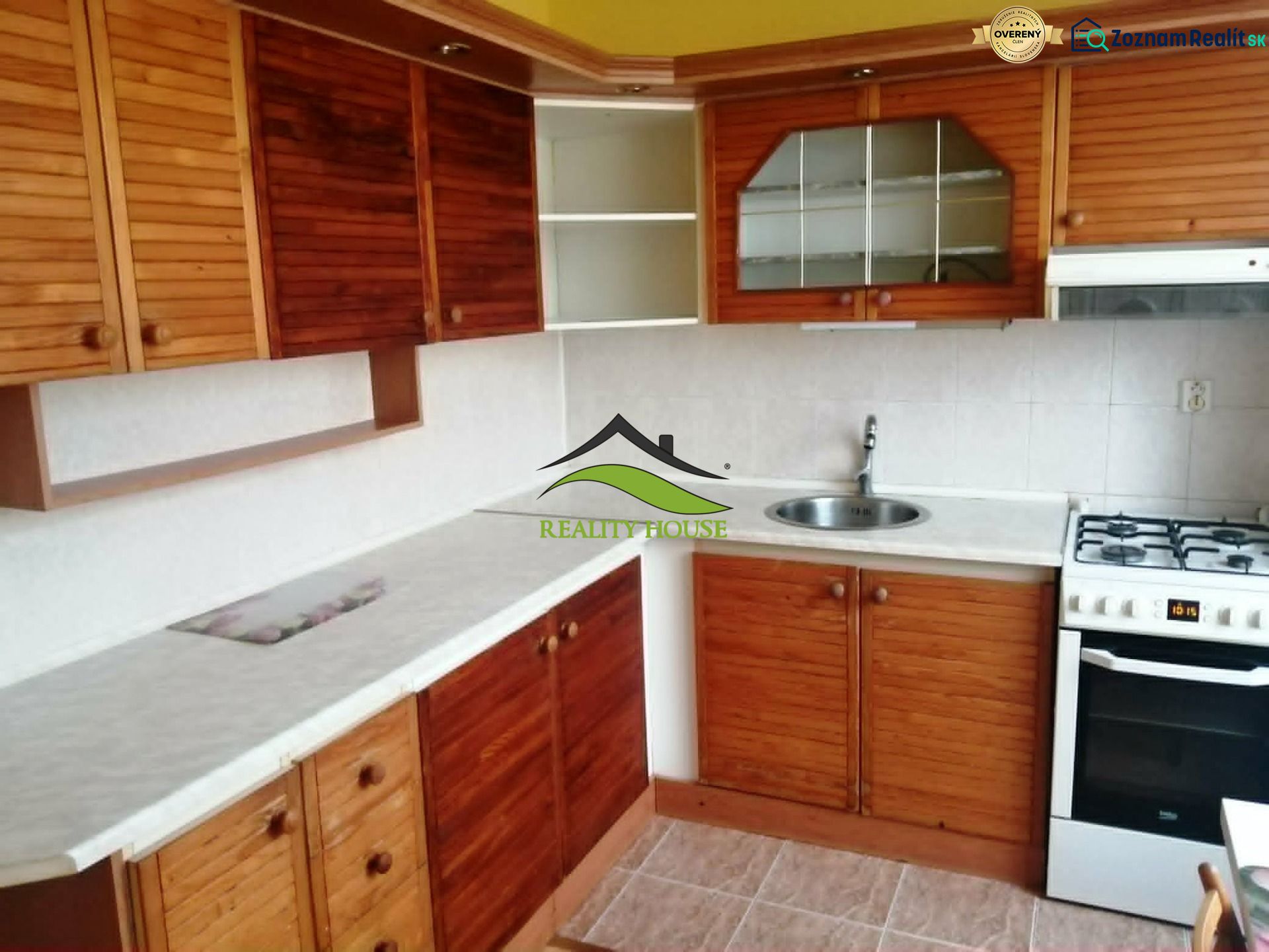A kitchen in a 3-room apartment with wooden cabinets and a white countertop.