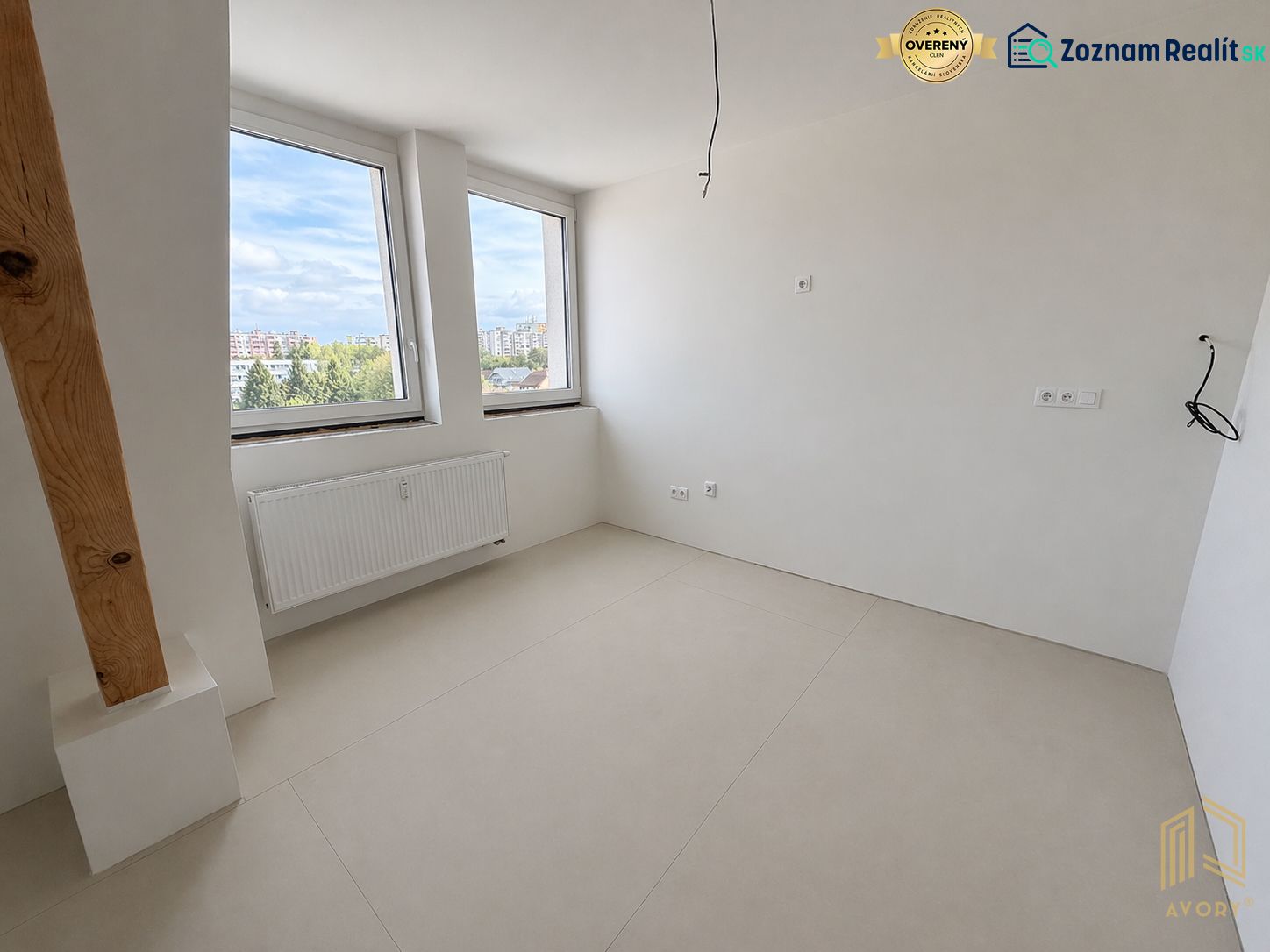A room of a 2-room apartment with large windows and a floor with a wooden decor.