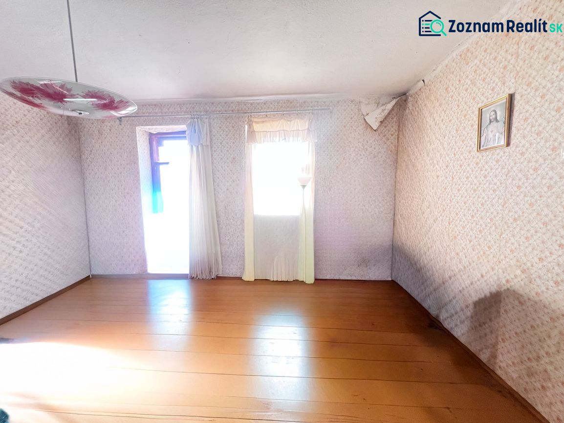 A room in a family house with a wooden decor floor, a floral chandelier, and a painting on the wall.