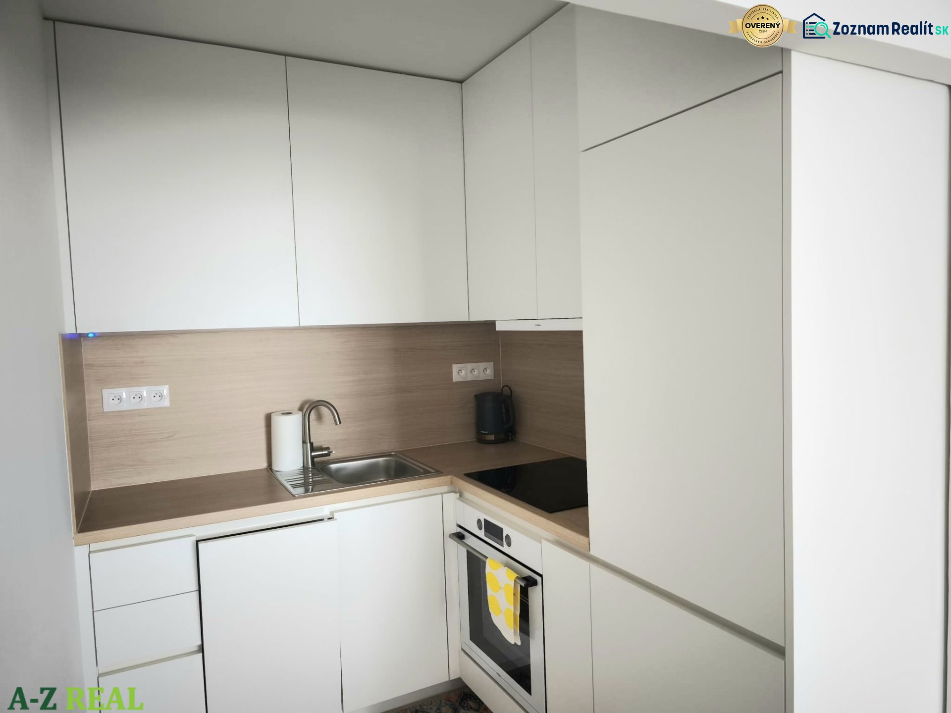 A kitchen with white cabinets and a stainless steel sink in a two-room apartment.