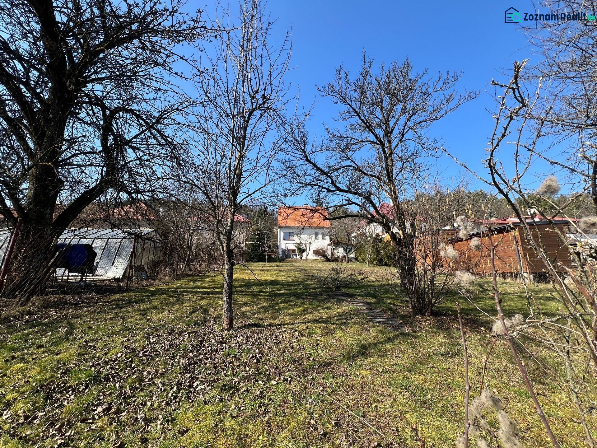A garden in the Banská Bystrica district around a family house with a lawn and trees.