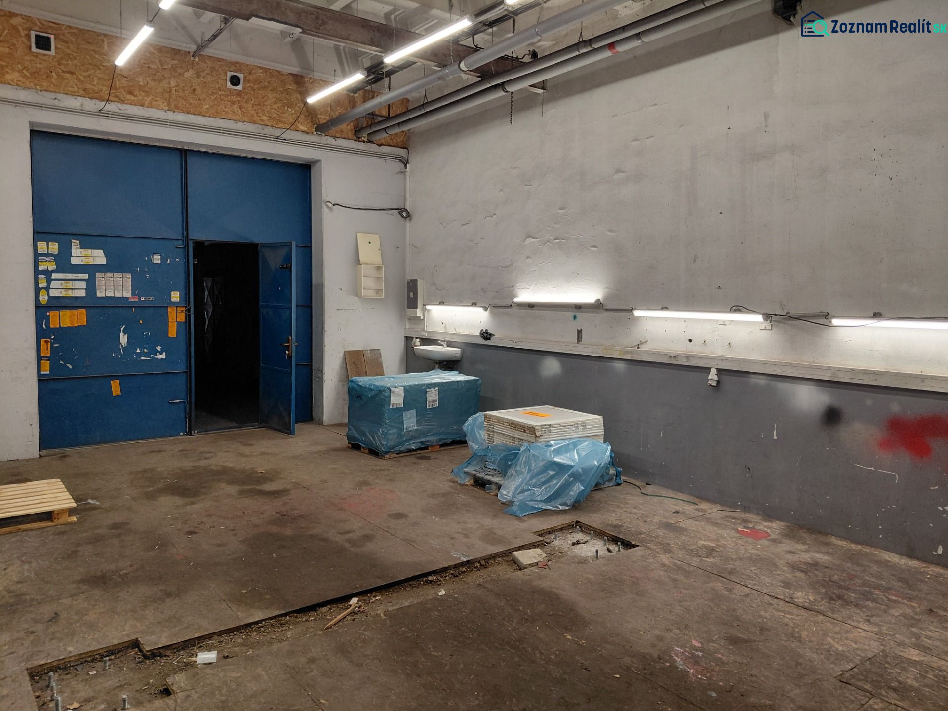 Warehouses and halls with blue doors, lighting, and materials on the floor with a wooden decor.