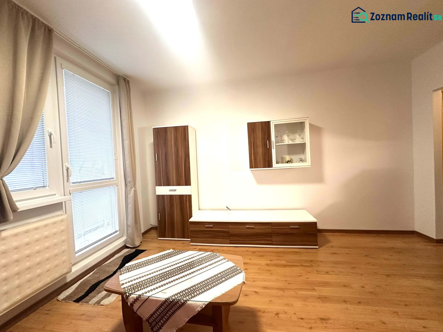 Recreational apartment with wood-patterned flooring, furniture, and a large window.