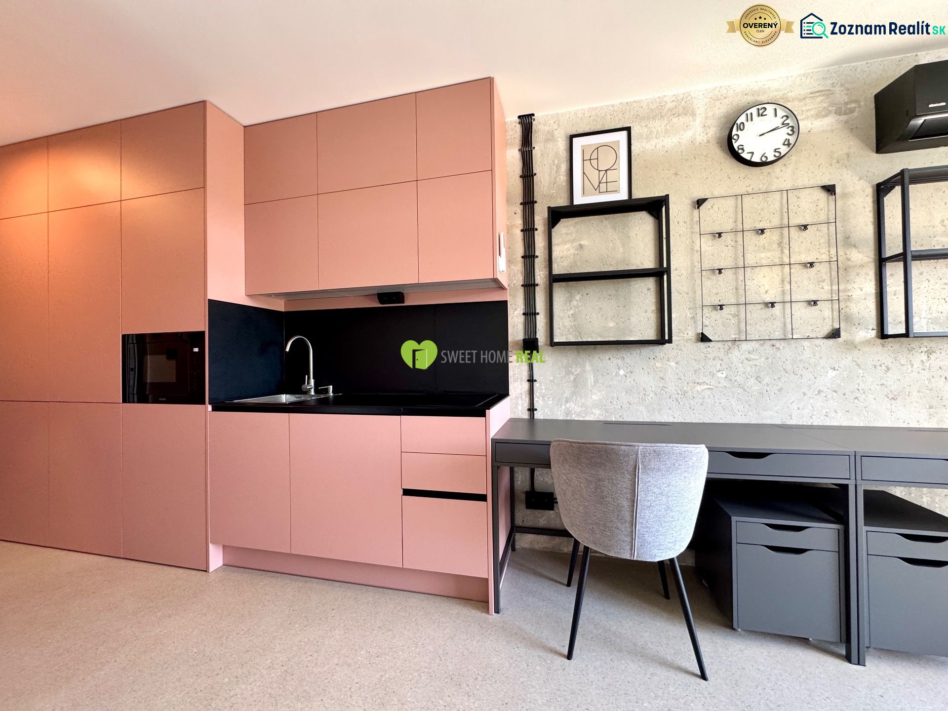 A kitchen and a work corner in a studio apartment with modern shelves and a clock on the wall.