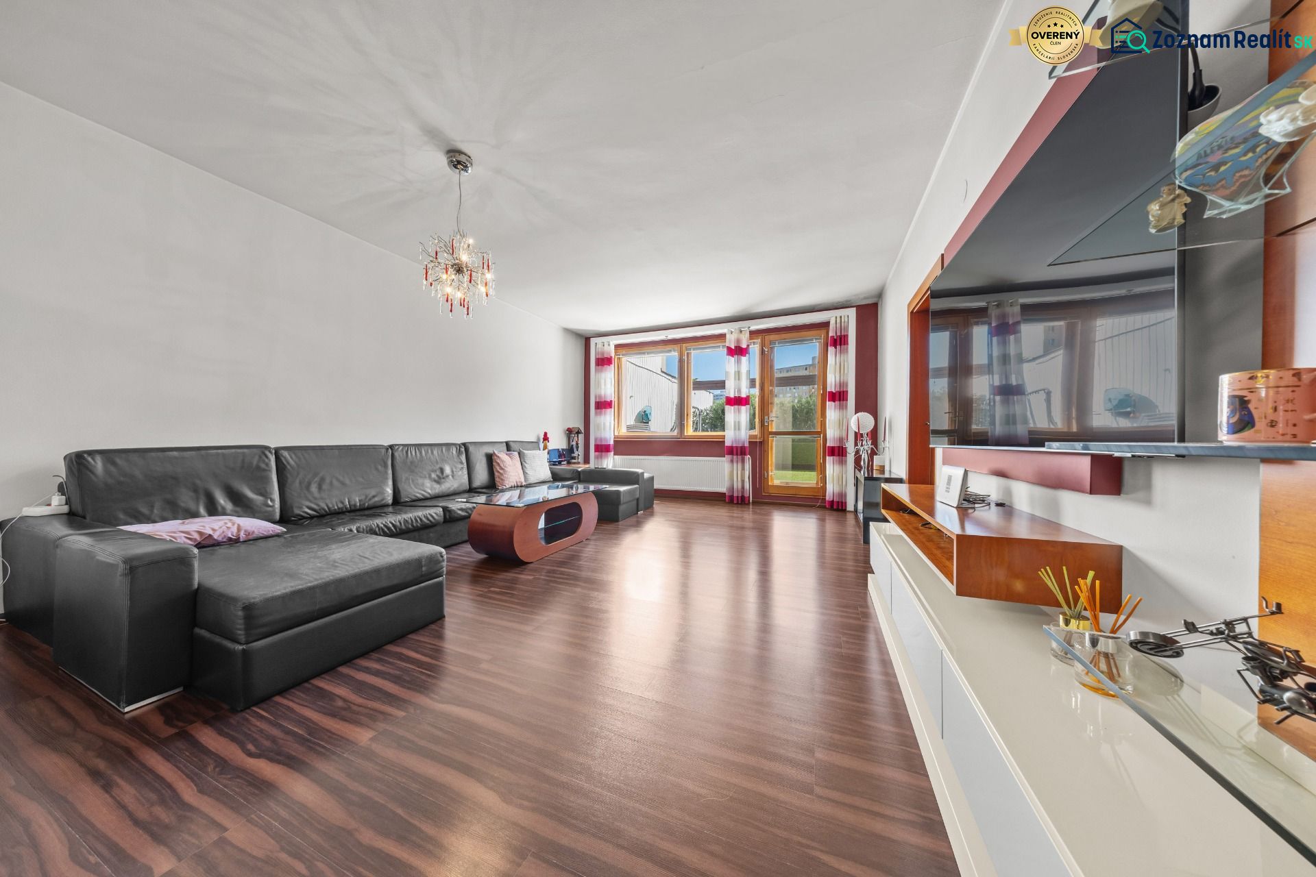 Living room in a family house with a large sofa and wood-patterned flooring.