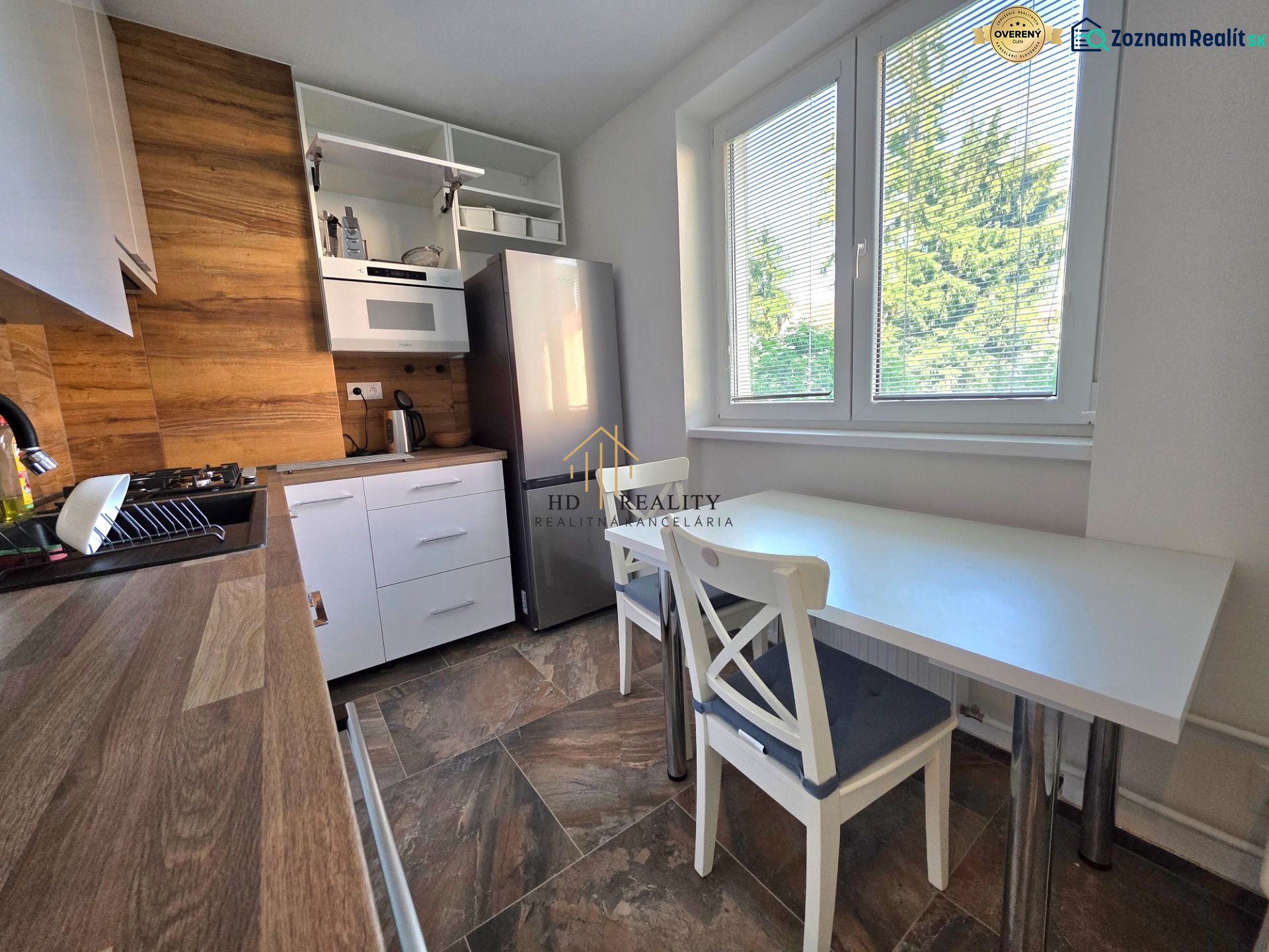 A kitchen in a 2-room apartment with a wooden decor and a view of greenery.