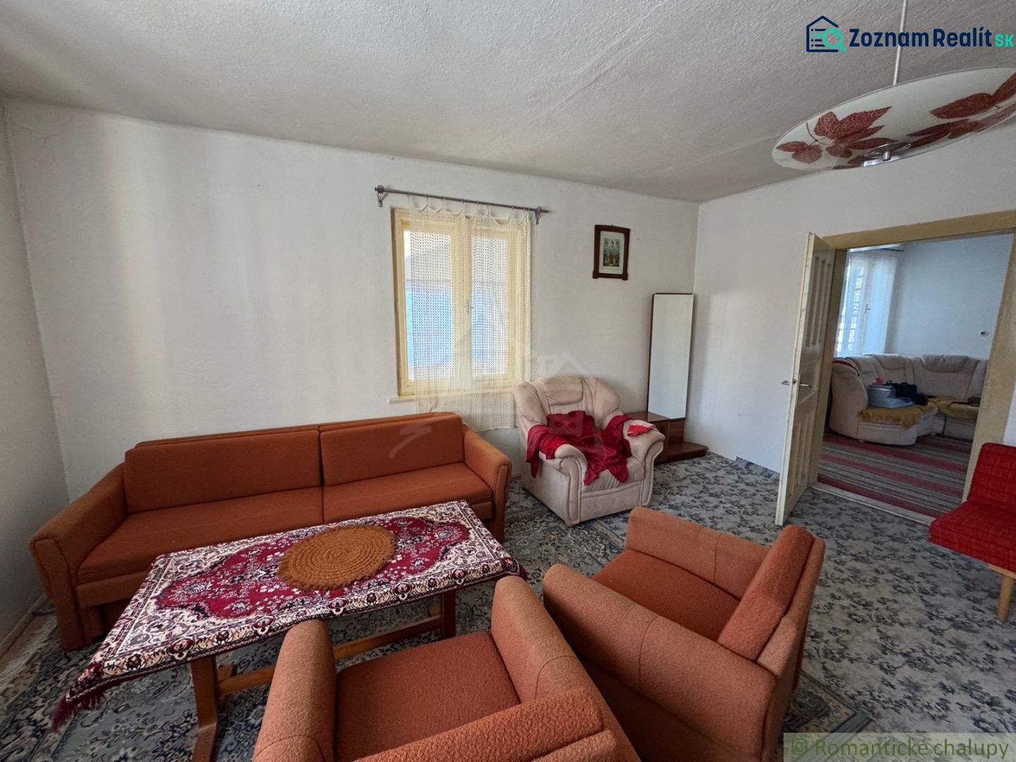 Living room in a family house with an orange sofa and a patterned carpet.