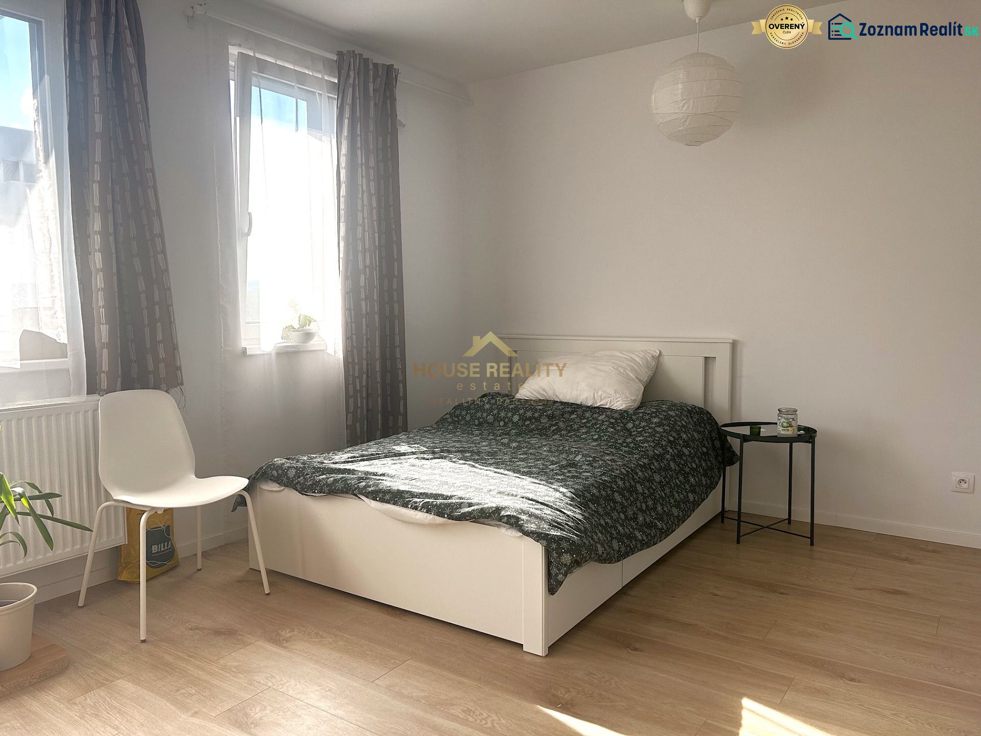 A bright room in a one-room apartment with a bed and a wooden decor floor.