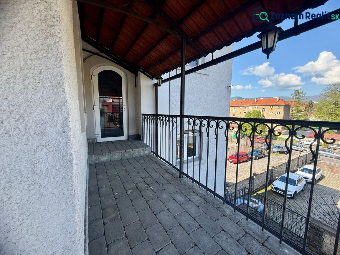 A balcony with an iron railing and a view of a parking lot in Banská Bystrica. Unusual properties.