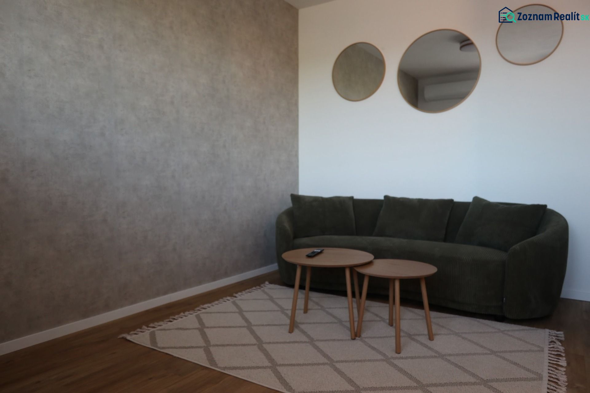Living room in a two-room apartment with a green sofa, round tables, and three mirrors.