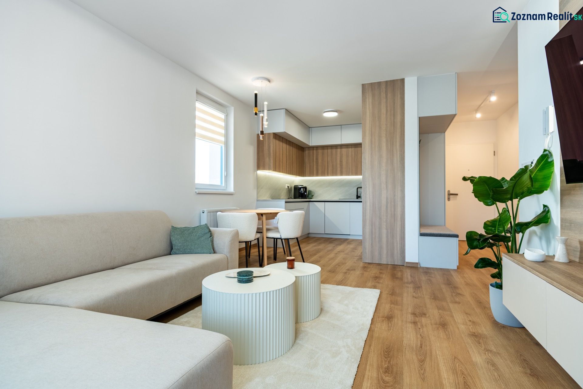 Living room connected with the kitchen in a 3-room apartment with a wooden decor floor.