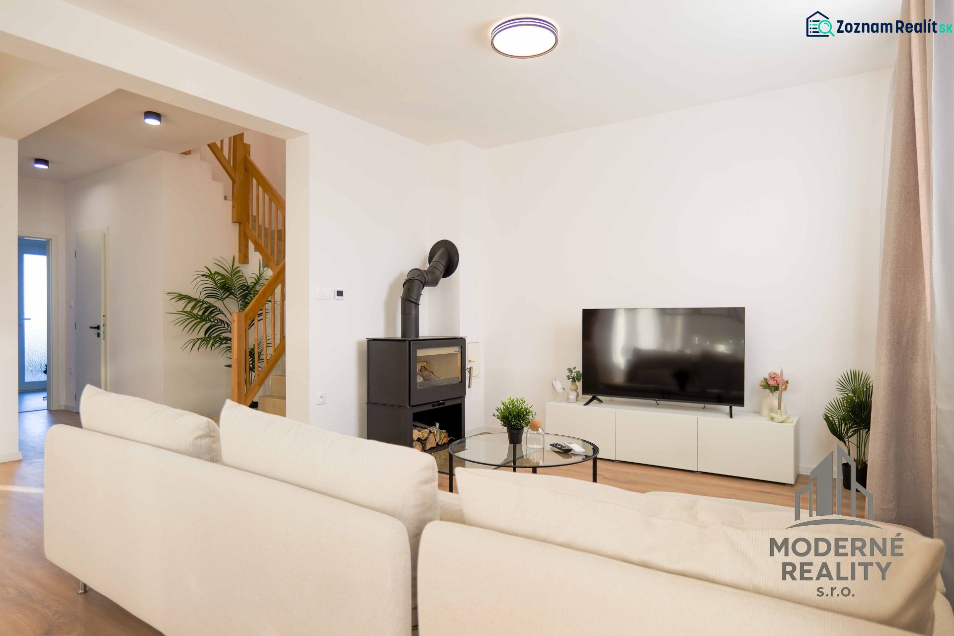Living room in a family house with a television, fireplace, and wooden decor flooring.