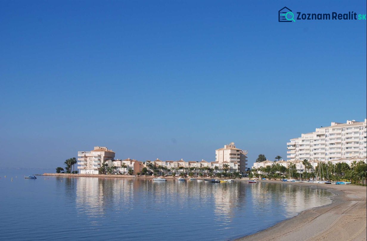 The coast with holiday apartments in La Manga del Mar Menor by the calm sea and blue sky.