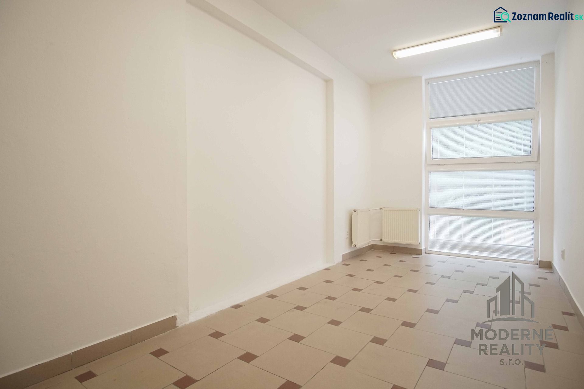 The interior of an office with large windows and light-colored tiles on the floor.