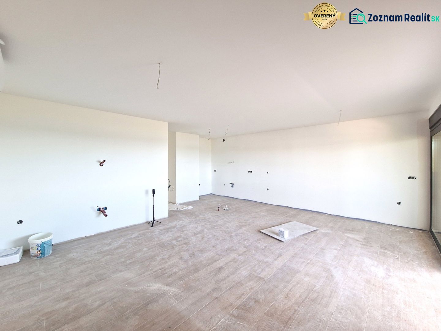 A spacious room of a 3-room apartment with a wooden decor floor and a large window.