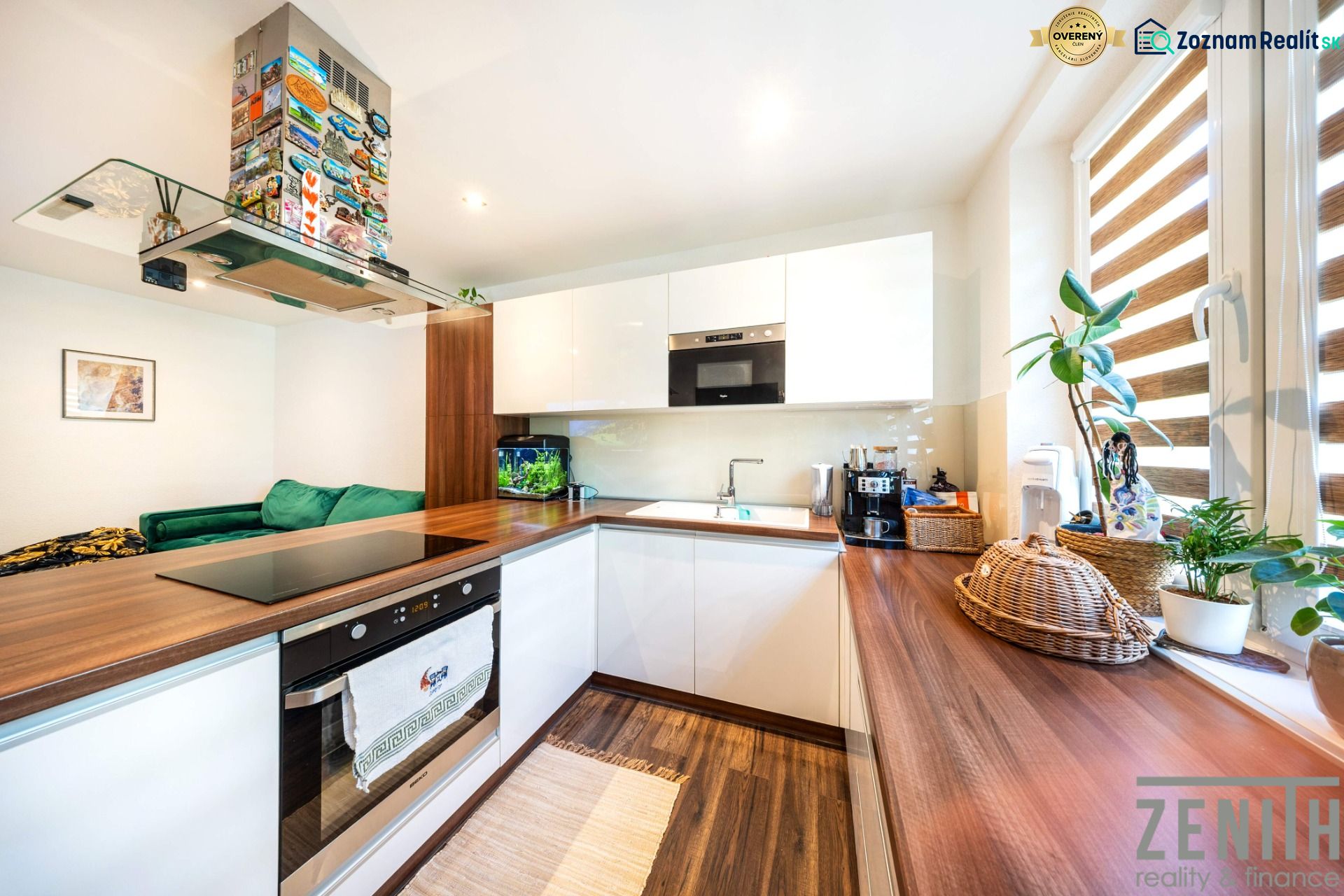 A kitchen in a 3-room apartment with a wood-decor floor, houseplants, and modern appliances.