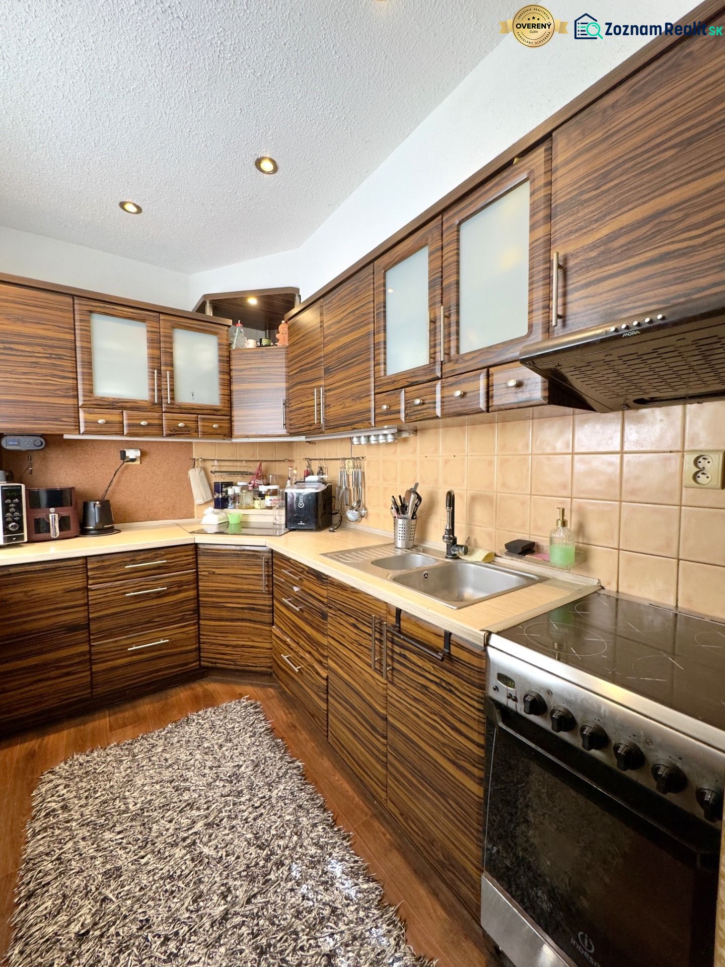 A kitchen in a 4-room apartment with a wood-patterned floor and appliances.