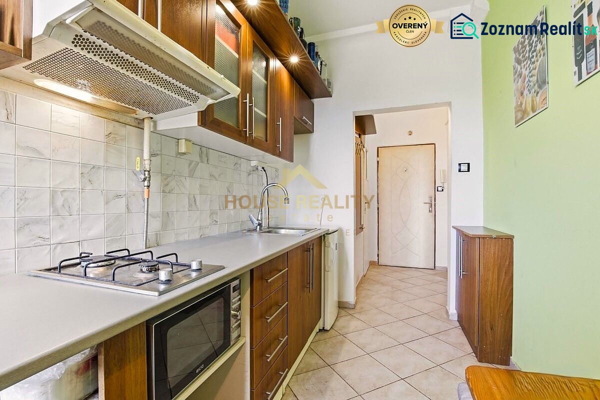 A kitchen in a 2-room apartment with a gas stove, microwave, and storage space.