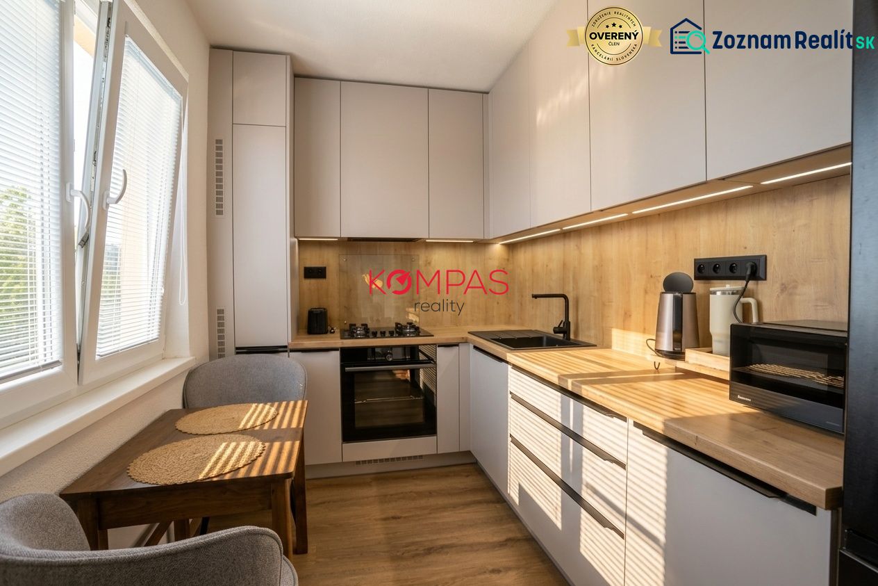 A kitchen in a 2-room apartment with wooden decor cabinets and a compact table.