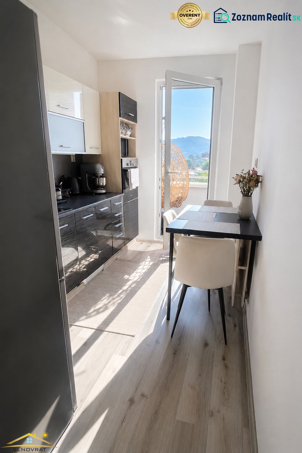 A kitchen in a 2-room apartment with a wooden decor floor and a view of the exterior.