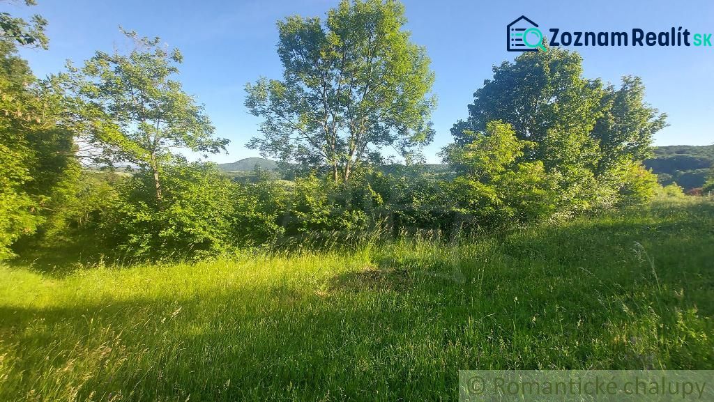 Gardens in Podkylava with a lawn, trees, and a view of nature under a blue sky.