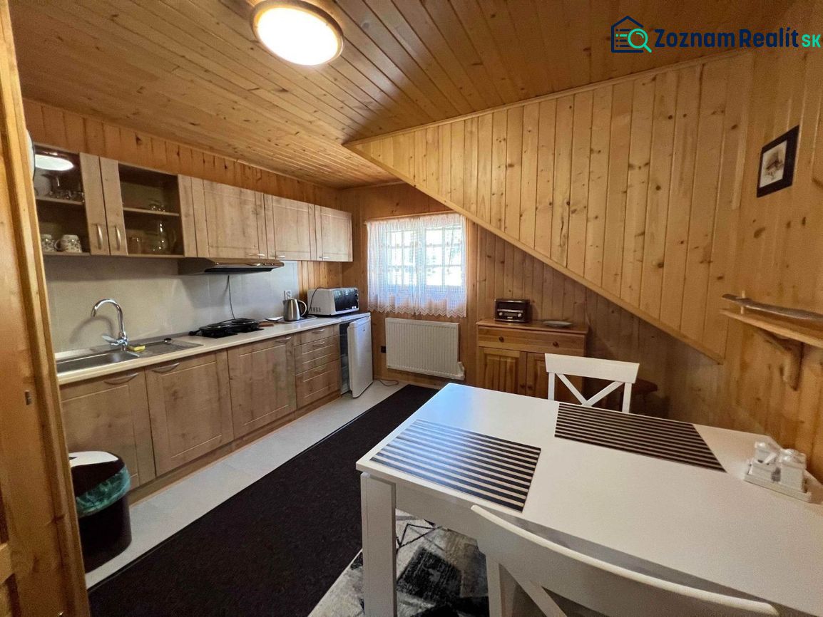 A kitchen in a family house with wooden paneling, a white table, and a countertop.