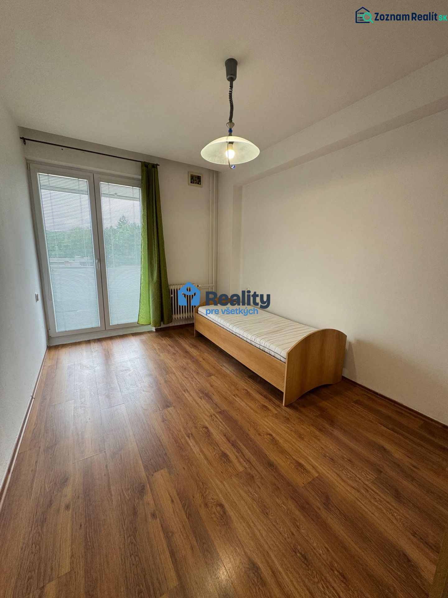 A room in a 2-bedroom apartment with a wood-patterned floor and a bed.