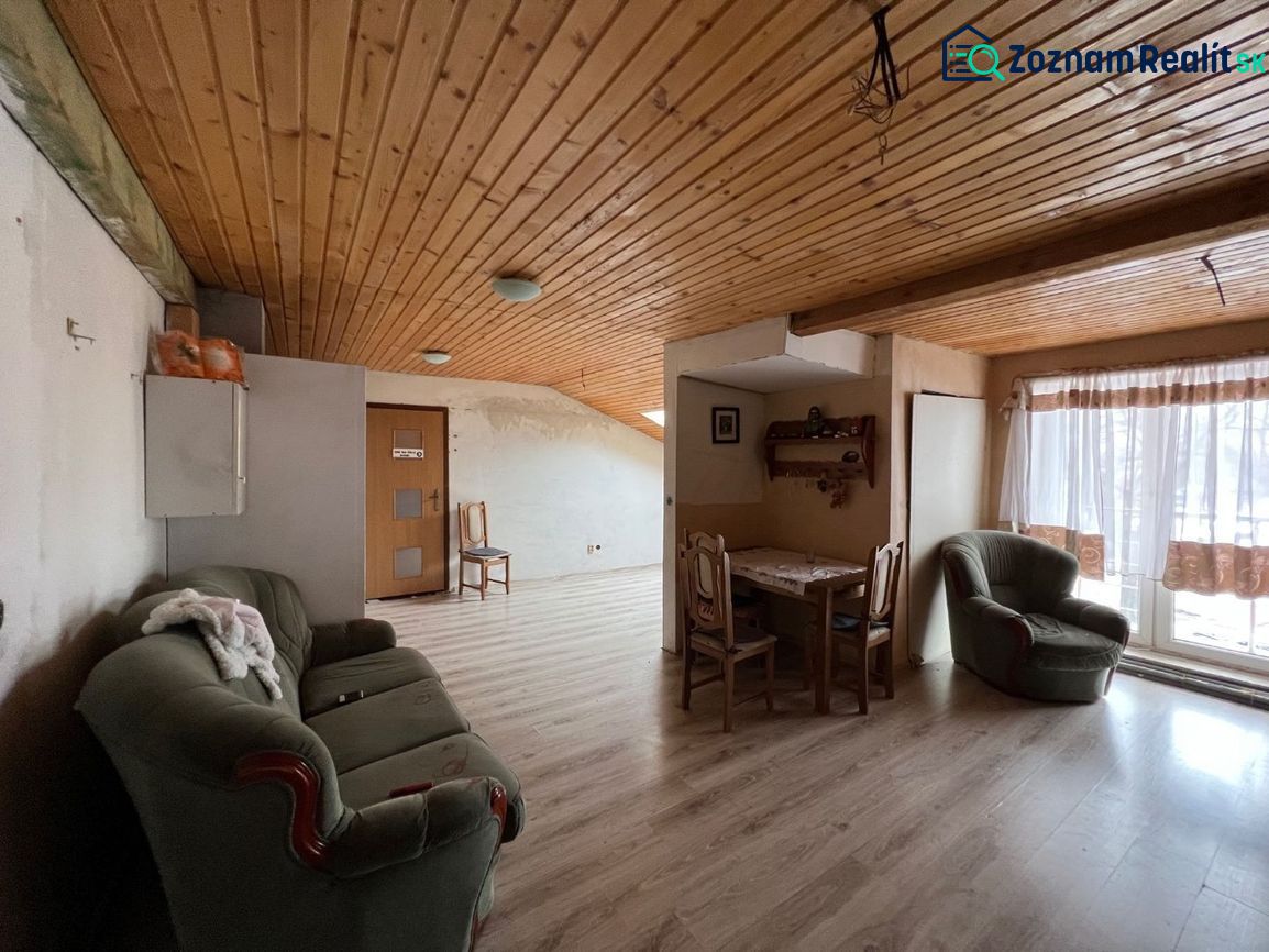 Living room in a family house with a wooden decor floor, a sofa, and a dining area.