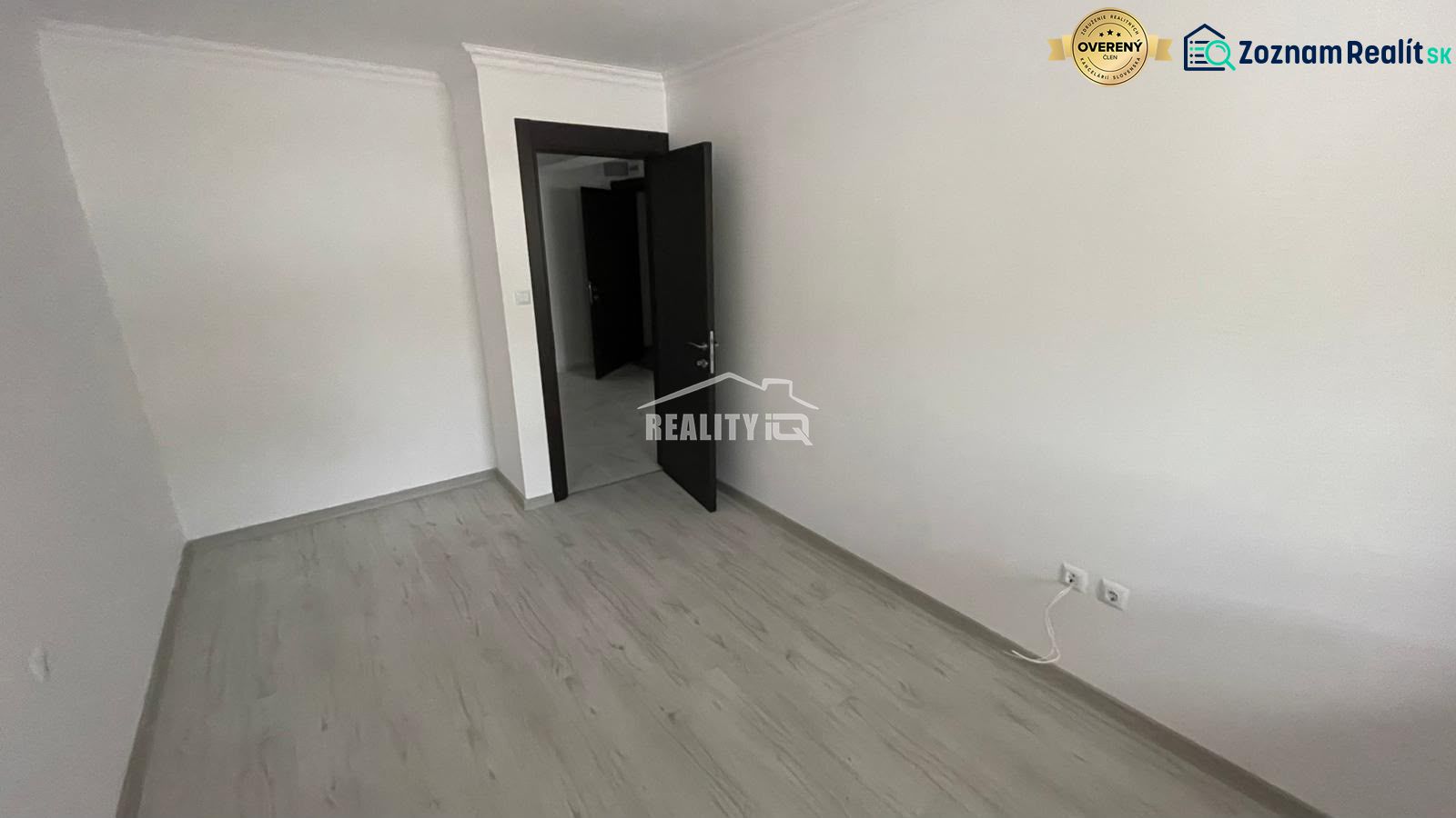 An empty room with a wooden floor and a door in a two-room apartment.