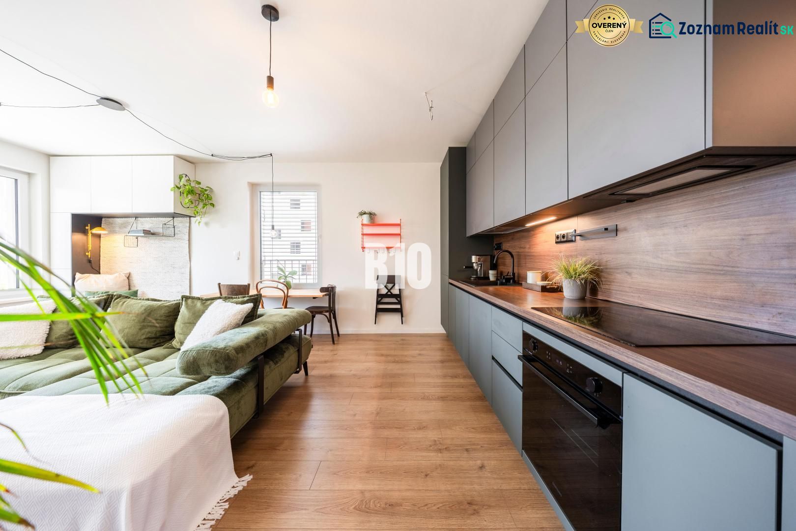 A kitchen in a 3-room apartment with a sofa and wooden decor flooring.