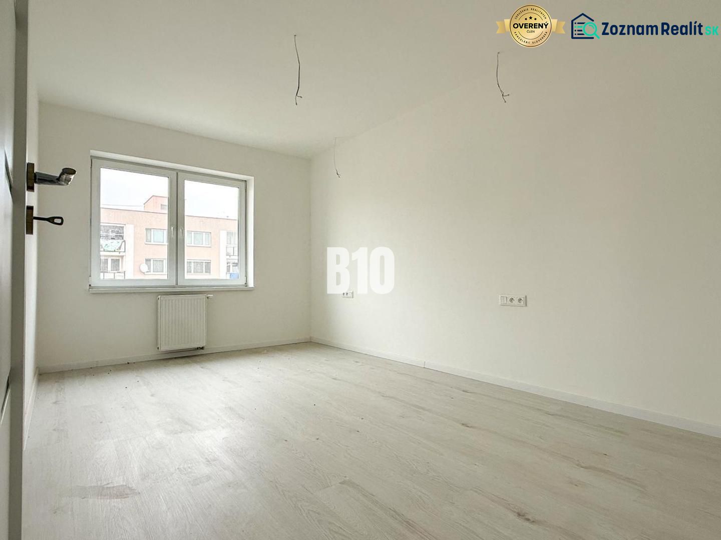 Interior of a 2-room apartment with a wooden decor floor, large window, and radiator.