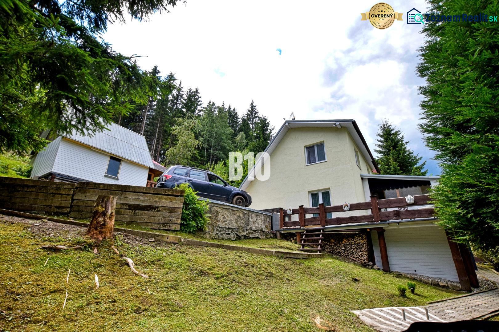 A cottage in nature in Olešná, surrounded by coniferous trees and lush lawn.